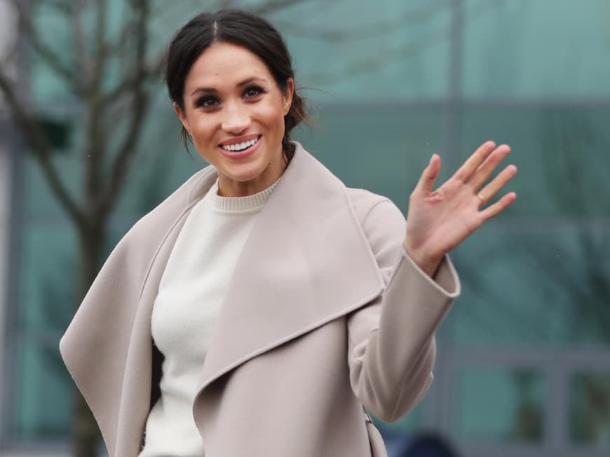 Meghan Markle in einem hellen Kleid und Mantel