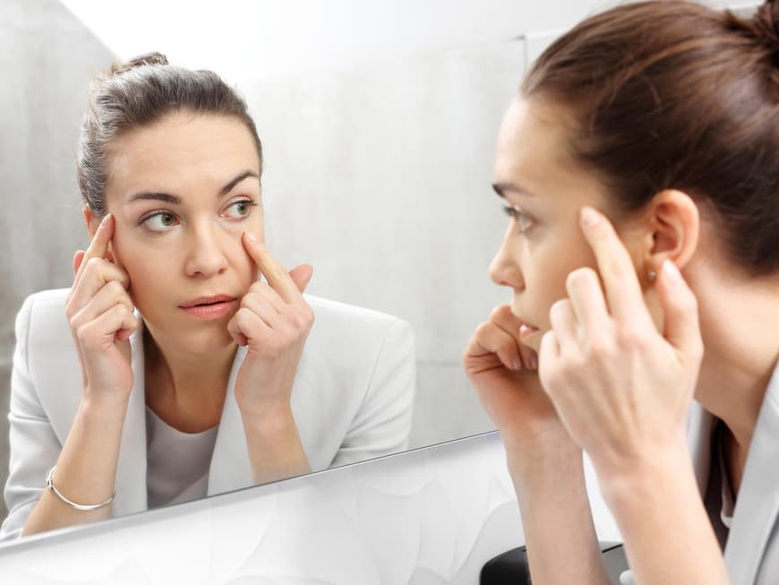 Frau betrachtet sich im Spiegel